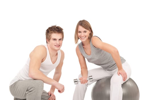Fitness - Young healthy couple training with weights and ball on white background