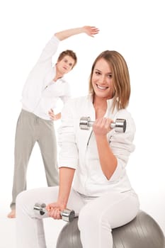 Fitness - Young healthy couple training with weights and ball on white background