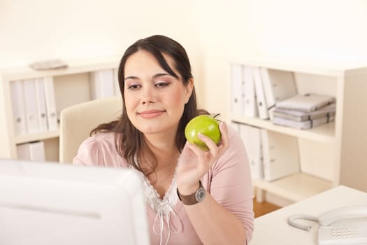 Young happy businesswoman holding apple at office having snack