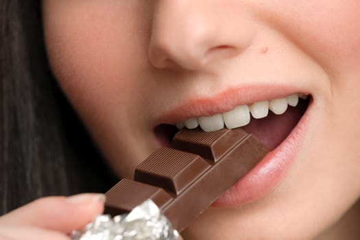 Chocolate - close-up of young woman bite sweets