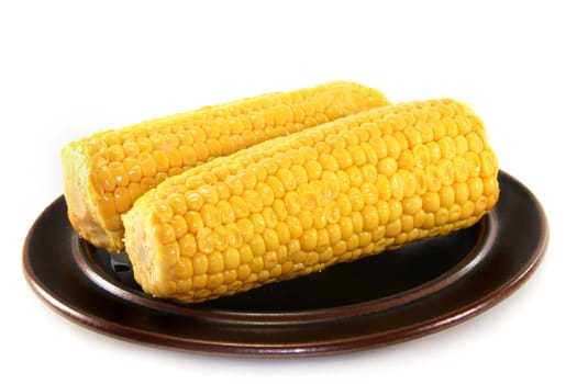 two corn on the cob on a brown plate