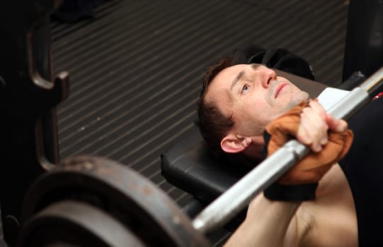 bodybuilding workout in gym. Male lifting free weights training pecks using barbell.
