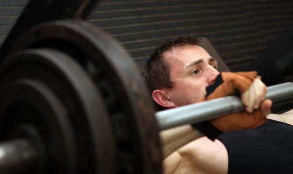bodybuilding workout in gym. Male lifting free weights training pecks using barbell.