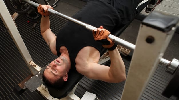 bodybuilding workout in gym. Male lifting barbell. man under exercise equipment training upper body strength