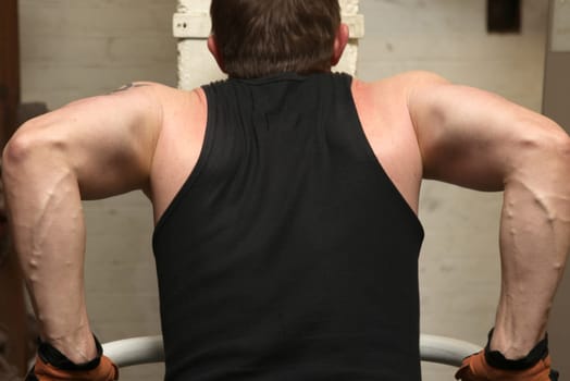 training biceps and triceps in gym. man exercise lifting himself showing muscles