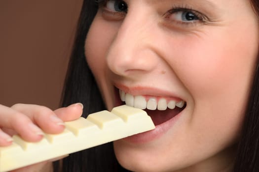 Chocolate - close-up of young woman enjoy sweets on brown background