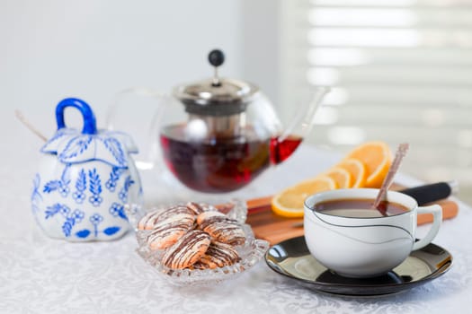 A spread of tea, cookies, and lemon on a white tablecloth
