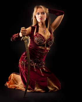 Beauty arabian woman sit with saber on black background
