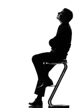 silhouette caucasian business man thinking pensive sititting on foot stool full length on studio isolated white background