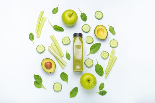 Bottle of green smoothie surrounded by green fruit and vegetables: apples, avocado, spinach, celery sticks, cucumber on white simple background top view. Diet, healthy nutrition, detox concept