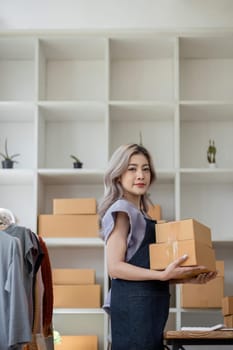 Online business concept, Asian business women holds parcel boxes of product for delivery to client.