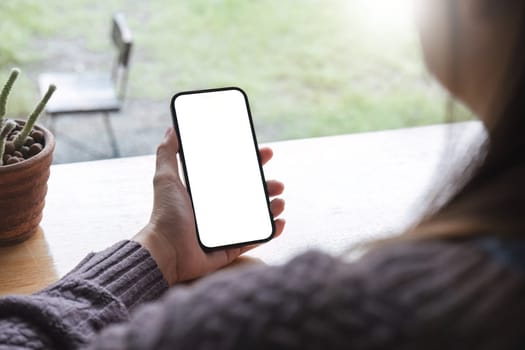 Mockup image of closeup woman hand holding mobile phone with blank white smartphone screen at the outdoor..