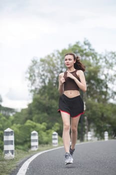 Young sporty woman jogging in the green park in the evening.