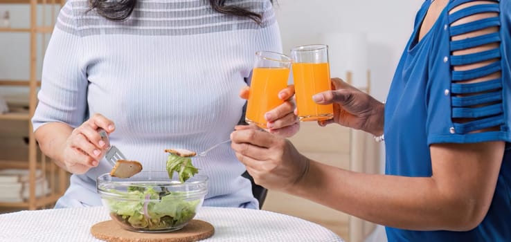 Two Asian woman enjoys talking with her friends while having a healthy food together..