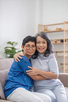 Two retired Asian women hug as they meet and have fun in the living room..