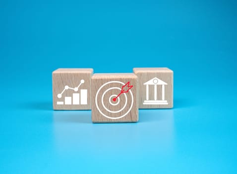 wooden block which prints a target icon and business symbol on light blue background. Business goals and objectives concept. business competition. business target concept.