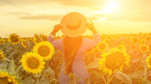 Woman sunflower field. Happy girl in blue dress and straw hat posing in a vast field of sunflowers at sunset. Summer time