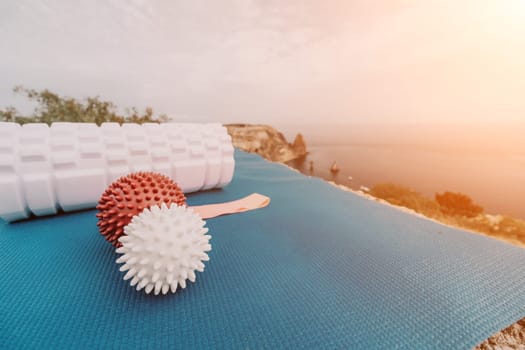 Middle aged well looking woman with black hair doing Pilates with the ring on the yoga mat near the sea on the pebble beach. Female fitness yoga concept. Healthy lifestyle, harmony and meditation.