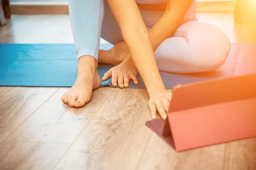 Young athletic attractive woman practicing yoga doing exercises. Works out at home or in a yoga studio, sportswear, blue pants and a full-length top indoors. Healthy lifestyle concept.