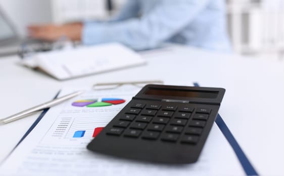 The black calculator lies on a chessboard. Background for calculating the business strategy calculation.