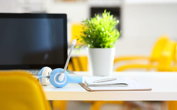 Empty remote office workplace with laptop pc and headset closeup. Receptionist or secretary of contact data center desktop keyboard device desk table ip telephony or callcenter voice message system
