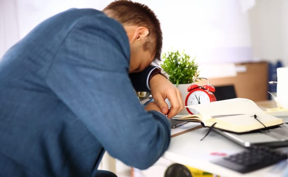 Tired office male clerk in suit take nap on table workplace full of exam papers. Sleepy white collar career frustration freelance employment fail study problem low energy down