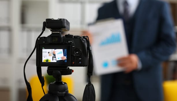 Male in suit and tie show stats graph pad making promo videoblog or photo session in office camcorder to tripod closeup. Vlogger selfie sale solution or finance advisor management information