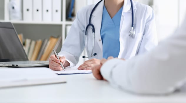 Stethoscope head lying on medical forms closeup while medicine doctor working in background. Patient history list visit check 911 medical calculation and statistics healthy lifestyle concept