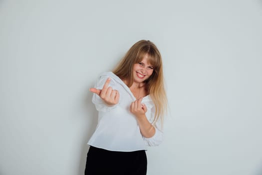 Cheerful woman calls her finger to come here on a light background in the room