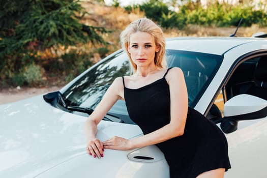 A woman stands near a white car Travel