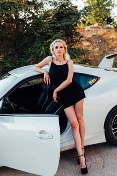 A woman stands near a white car Travel