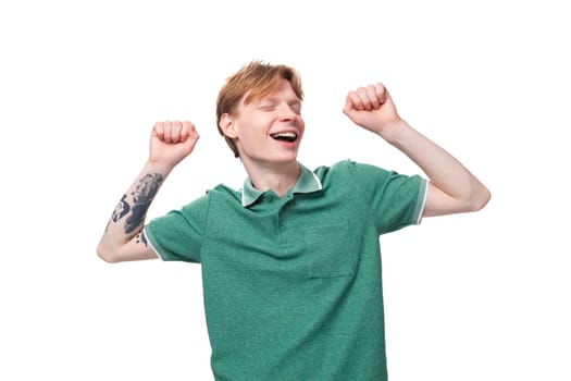 joyful happy young redhead guy in green shirt looking at camera.