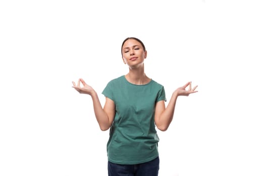 30 year old slender European brunette woman with a ponytail hairstyle dressed in a green T-shirt is meditating.