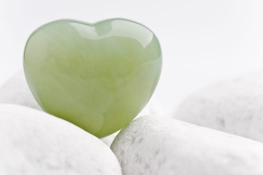 Green quartz mineral heart as a symbol of love on white stones