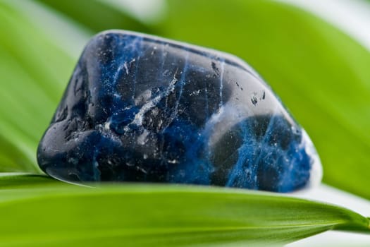 Natural stone sodalite shines in beautiful colors on white background