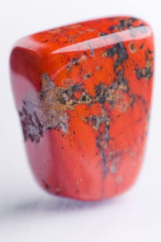 Natural stone red jasper shines in beautiful colors on a white background