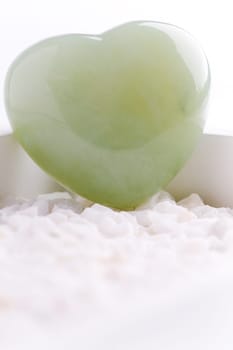 Green quartz mineral heart as a symbol of love on white stones