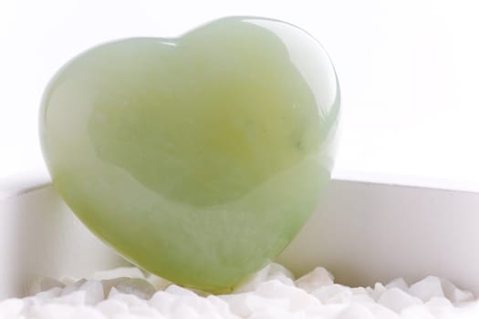 Green quartz mineral heart as a symbol of love on white stones