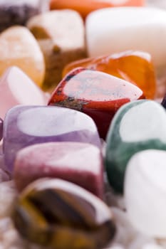 Many different natural stones in beautiful colours on a white background