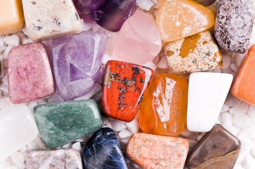 Many different natural stones in beautiful colours on a white background