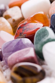 Many different natural stones in beautiful colours on a white background