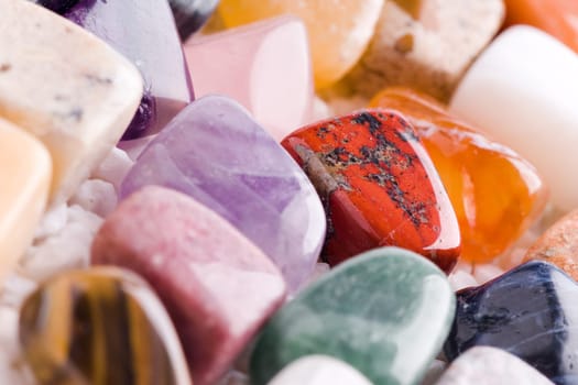 Many different natural stones in beautiful colours on a white background