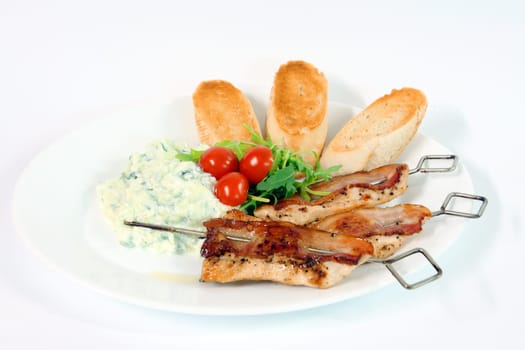 Greek food - tzatziki, chicken souvlaki with bacon and baguette on white background