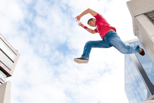 Young man jumping in front of sky and house front