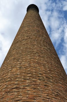 Weathered industrial brick chimney of an abandoned factory.