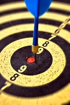 Dartboard target and blue dart arrow. Selective focus.