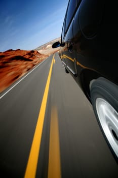 Car driving down rural road in Wyoming. Focus on mirror. Mounted camera, natural motion blur.