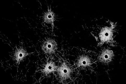 Broken glass - multiple actual bullet holes in glass isolated on black
