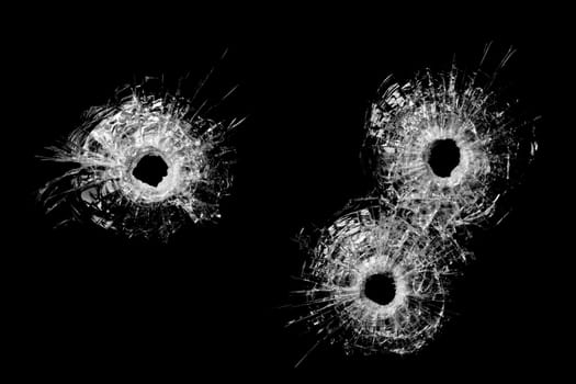 bullet holes in glass isolated on black - bullet holes from .40 handgun closeup