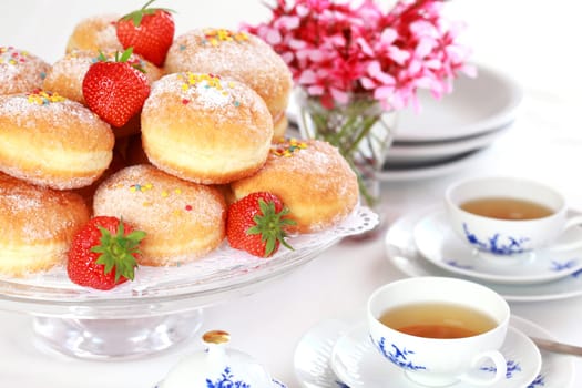 Doughnut filled with strawberry jam - German national dish with cup of tea